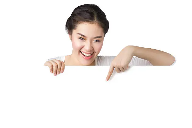 Photo of Young smiley Asian woman showing and pointing at blank billboard