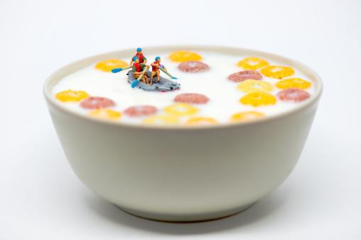 Rafting in a bowl of colorful cereal with milk. Healthy breakfast concept. Macro photo