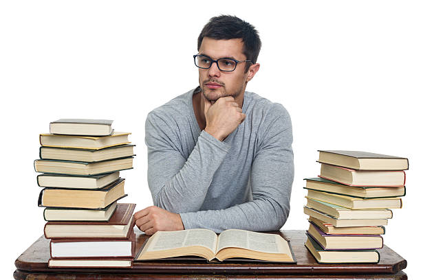 istock Young man in glasses reads book at table 515002928