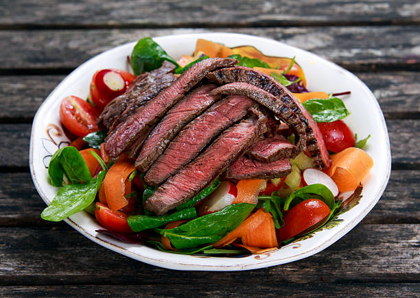 Spicy Beef Slices Meat Salad with vegetables Spicy Beef Slices Meat Salad with Carrots, Tomatoes, Cucumber, Parsley, Radish and Salad leaves Spinach, rocket, red ruby chard on old wooden table steak salad stock pictures, royalty-free photos & images