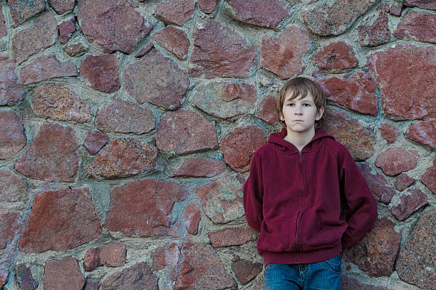 Adolescente ragazzo appoggiato di granito rosso massi parete - foto stock