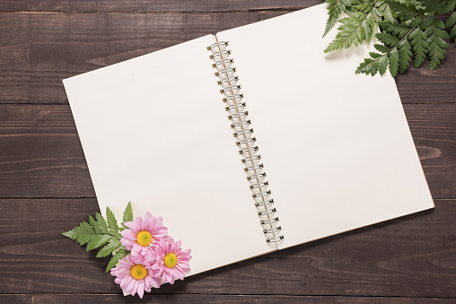 Pink flowers are on a notebook space for your text.