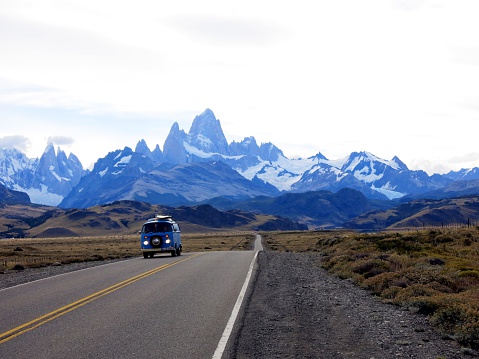 El Chalten, Los Glaciares National Park, Argentina - Febuary 12, 2016:A blue VW bus driving away from the silhouette of Fitz-Roy and Cerro Torre in the Los Glaciares National Park in Argentina