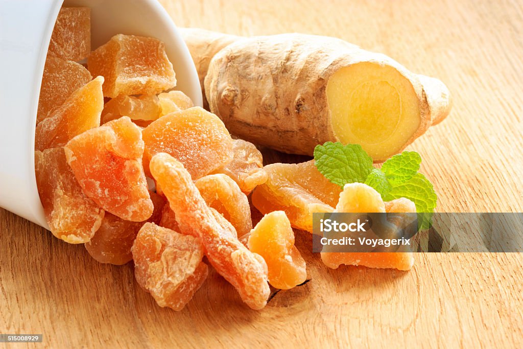 Closeup root and candied ginger on wooden table Closeup dried candied crystallized ginger pieces and raw root on wooden table. Healthy food, home remedy for nausea, colds. Candy Stock Photo