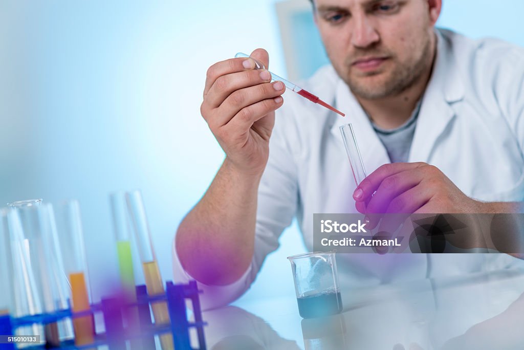 Scientist Scientist experimenting with chemicals in laboratory. Adult Stock Photo