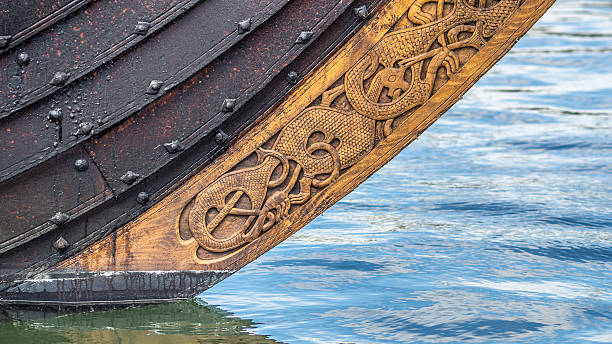 Viking ship bow with wood carving ornaments near the waterline stock photo
