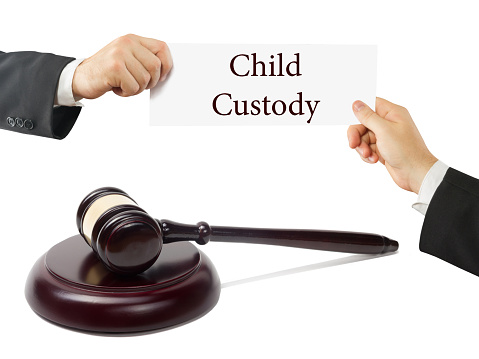 Wooden judges gavel on table in a courtroom or law enforcement office. Lawyer Hands holding business card with text Child Custody.