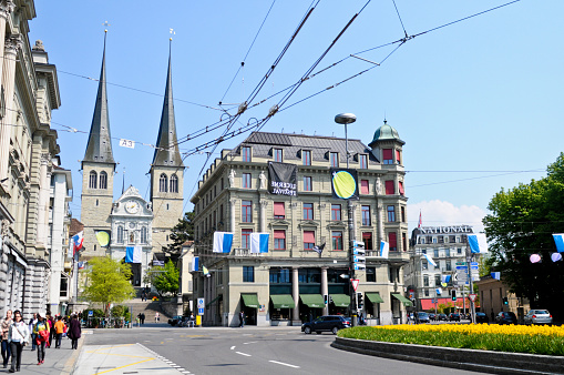 Lucerne, Switzerland - April 17, 2011: Lucerne City in Spring time with Street, Traffic and People Walking. In Background the huge St,Leodegar Church.