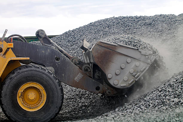 Auto Loader Drawing Gravel Up into Scoop Closeup shot of auto loader scoop, it is drawing gravel up into scoop from the pile. gravel mound stock pictures, royalty-free photos & images