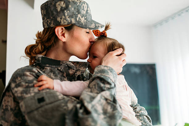 My Hero is back home. Military mom hugging with her child, little baby girl. Mother kissing her little girl. Having some happy time together. Mother just return from some of army missions. military lifestyle stock pictures, royalty-free photos & images