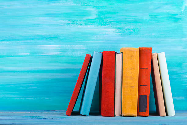 Stack of colorful books, grungy blue background, free copy space Vintage old hardback books on wooden shelf on the deck table, no labels, blank spine. Back to school. Education background