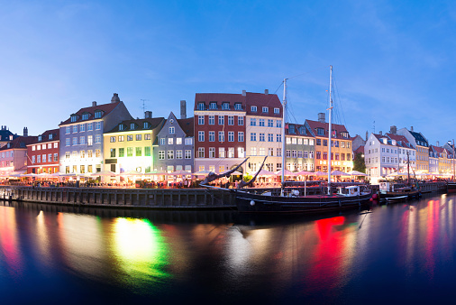 Wide angle panoramic view of the Nyhavn canal at twilight in Copenhagen, Denmark. Some movement in the boats due to the long exposure time.