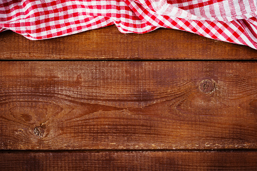 Plaid red and white tablecloth textile on wooden background. Food background