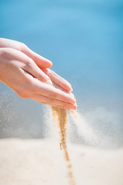 istock two hands sand through his fingers blue sky background 515070092