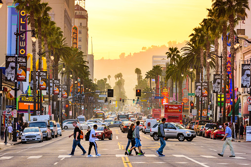 Los Angeles, USA - March 1, 2016: Pedestrians cross traffic on Hollywood Boulevard at dusk. The road serves as a theater district and major tourist attraction.