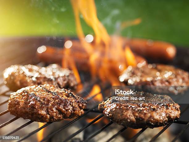 Hamburgers And Hotdogs Cooking On Flaming Grill Stock Photo - Download Image Now - Barbecue Grill, Burger, Barbecue - Meal