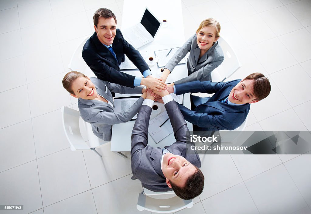 Happy partners Above view of business people with their hands on top of each other looking at camera Achievement Stock Photo