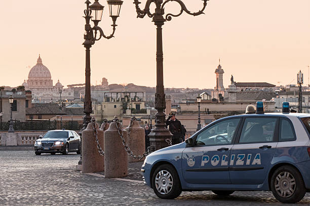 Rome, Italy - February 20, 2016: foreground, Italian police car on the square of the Quirinale Palace - it is the  official residence of the President of the Italian Republic - and St. Peter's dome on the background. Policeman is guarding the area. The surveillance has been strengthened after terroristic threats.