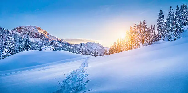 Photo of Winter wonderland in the Alps with mountain chalet at sunset
