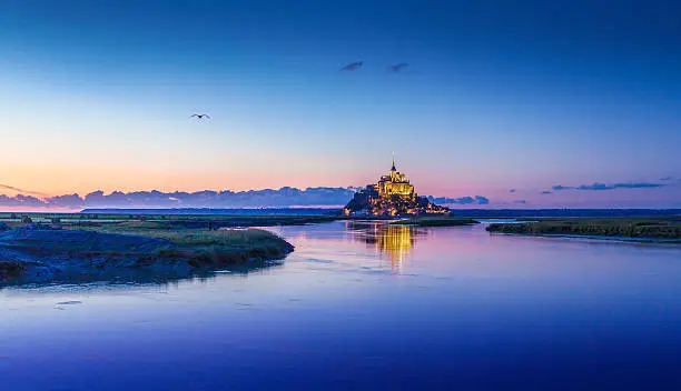 Panoramic view of famous Le Mont Saint-Michel tidal island in beautiful twilight during blue hour at dusk, Normandy, northern France