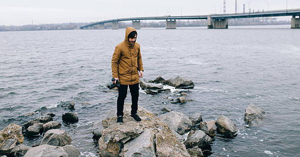 istock Photographer standing with camera on stone at river 515072324