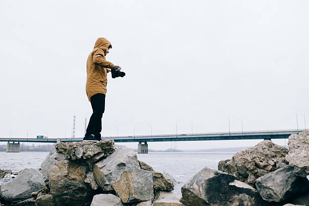 istock Photographer standing with camera on stone at river 515072652