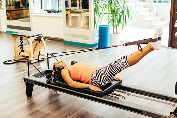 Young woman stretching on a pilates reformer