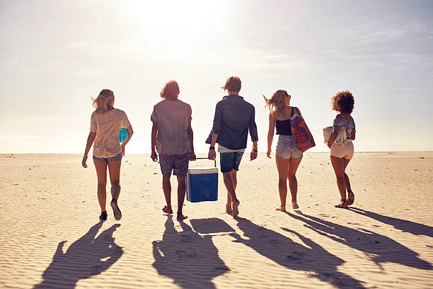 Young people on the beach carrying a cooler box