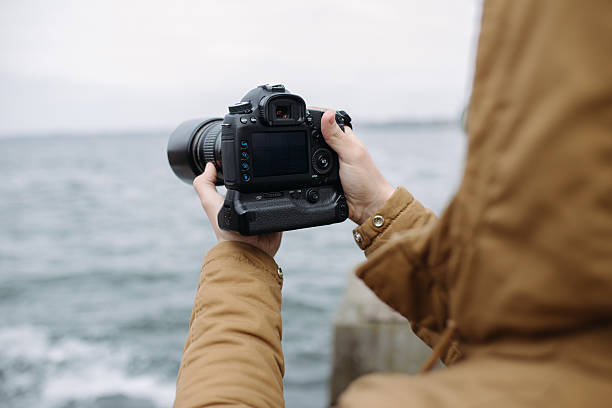 istock Unrecognizable man holding a camera and shooting sea wawe 515076456