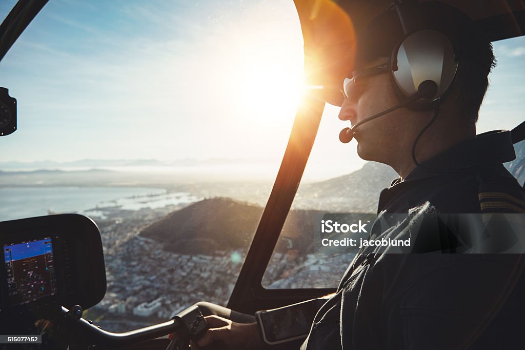Pilot flying a helicopter Close up of a male pilot flying a helicopter over city of Cape town on sunny day Helicopter Pilot Stock Photo