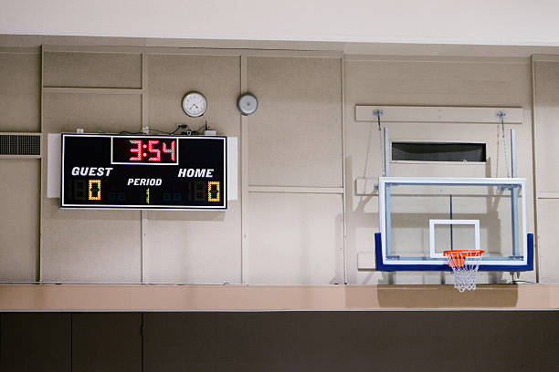 Basketball hoop and scoreboard in a school gym Basketball hoop and scoreboard on a wall of a school gym school sport high up tall stock pictures, royalty-free photos & images