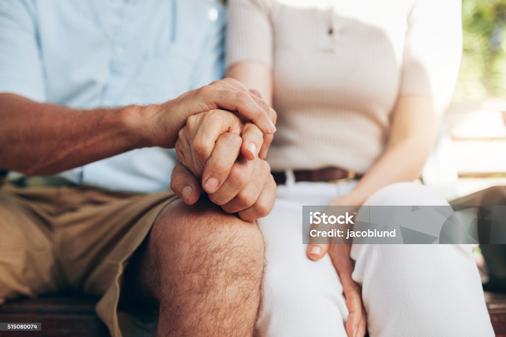 Loving couple sitting together and holding hands Close up shot of senior couple holding hand. Loving couple sitting together and holding hands. Focus on hands. Holding Hands Stock Photo