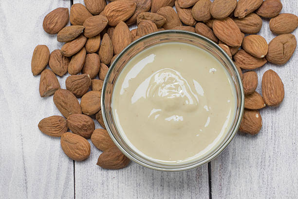 Top View on Almond Butter in Glass Bowl with Almonds stock photo
