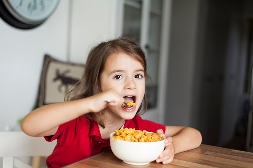 cute little girl sitting at home eating cornflakes