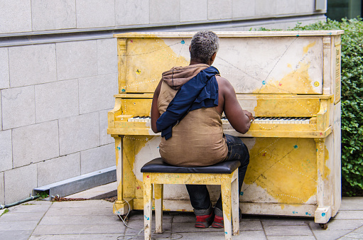 Montreal, Canada - July 26, 2014: Homeless man playing a piano on a street in Montreal, Quebec, Canada.