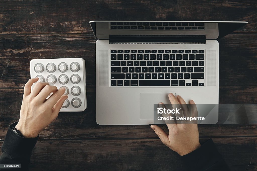 Two hands working on mixer and laptop top view Top view two hands working on retina laptop and wireless midi mixer control to make music or color grading Everything on vintage wooden tableTop view two hands accurately twist knobs on wireless midi mixer control Vintage wooden table isolated on side top view Balance Stock Photo