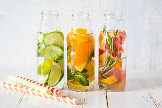 Selection of infused water in glass bottles, rustic wood background stock photo