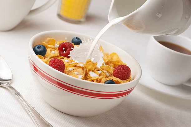 Milk Pouring on Cereal Bowl of cornflakes with milk and berries.  Good morning! corn flakes stock pictures, royalty-free photos & images