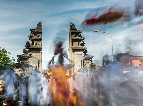 Bali, Indonesia - March 6, 2016: In extreme slow shutter speed, a Hindu procession takes place at the famous temple of Tanah Lot in Bali. Numerous Balinese people attend the special event and pray for the purification of their island before Nyepi, the Hindu new year.