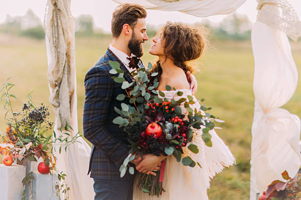 Wedding couple lovingly look at each other during ceremony Happy wedding couple lovingly look at each other during ceremony on the meadow. bride holding bouquet stock pictures, royalty-free photos & images
