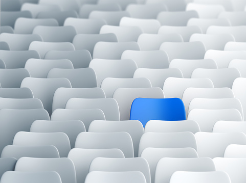 Blue chair in a lecture hall full of white ones. Individuality, discrimination and contrasts concept