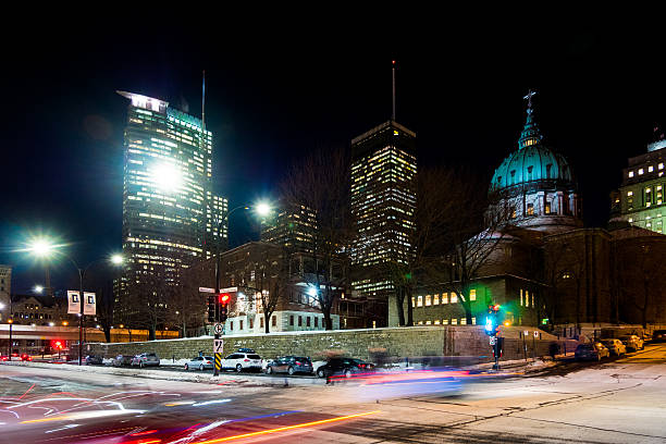 Instersection in Montreal, Canada Montreal, Canada - January 28, 2015: Light trails of cars driving past an intersection in Montreal, Canada with the Mary, Queen of the World Cathedral and other city buildings in the background. People can be seen walking along the side of the road. mary queen of the world cathedral stock pictures, royalty-free photos & images