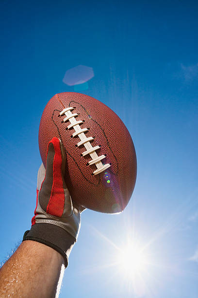 istock Football Held High in celebration against sun and sky 515167667