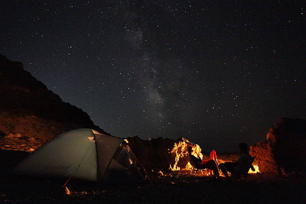istock Star-filled night sky, with tent, campfire and silhouette meadows 515168043