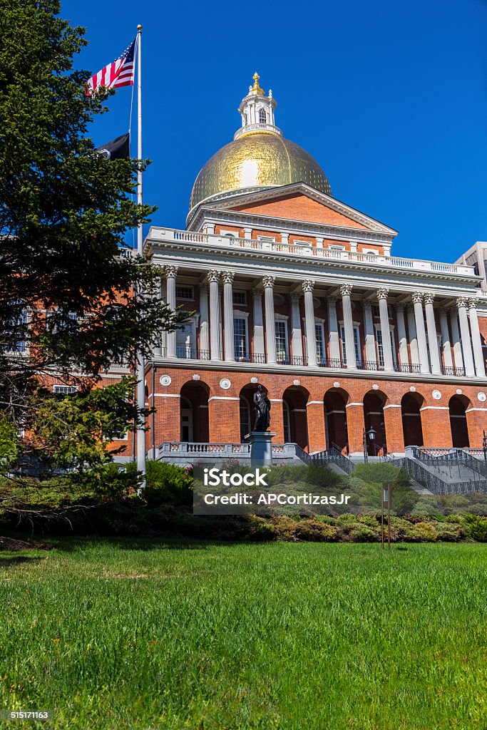 Massachusetts State House and Capital, USA XXLarge: Massachusetts State House and Capital, USA. Upward lefthand-side view with grass lawn in foreground. Includes American flag on pole. Some specular highlights on gold dome. American Flag Stock Photo
