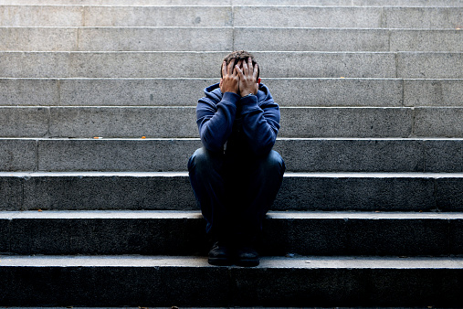 Young man suffering depression sitting on ground street concrete stairs