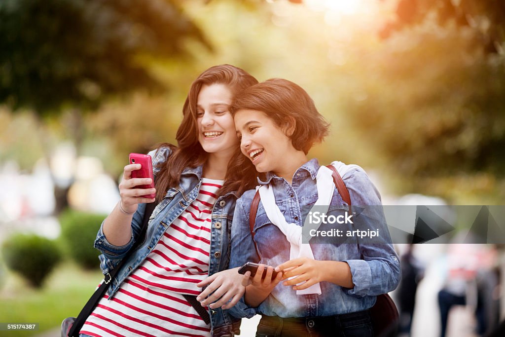 best friends two teenage girls having fun with their mobile phones Adult Stock Photo