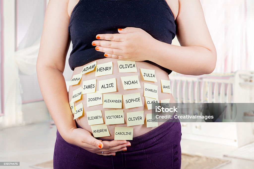 Pregnant belly with baby names choices Close up of pregnant belly with baby names choices on woman belly, shot in bedroom Baby - Human Age Stock Photo