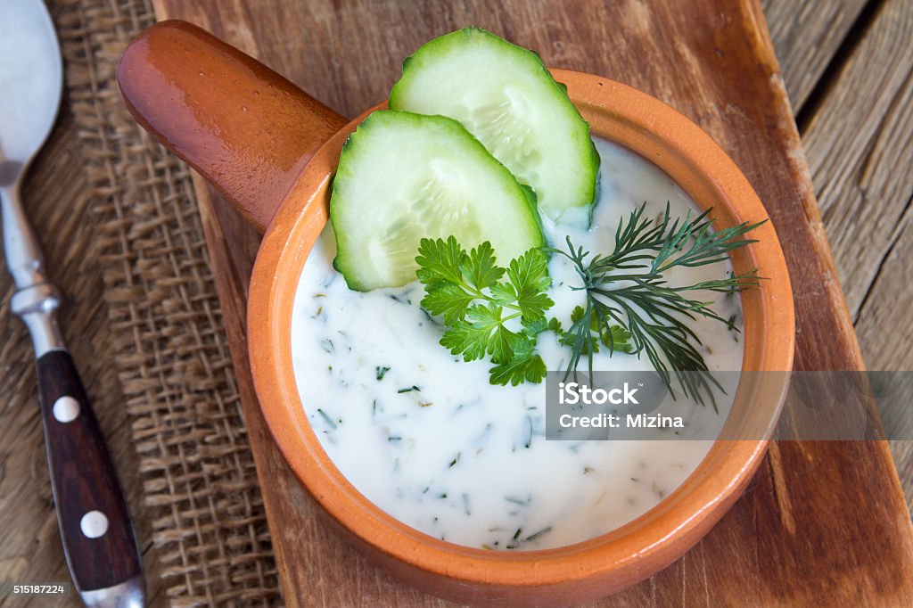 Tarator, cold soup Tarator, cold soup with cucumbers, yogurt and fresh herbs on wooden table Bulgaria Stock Photo