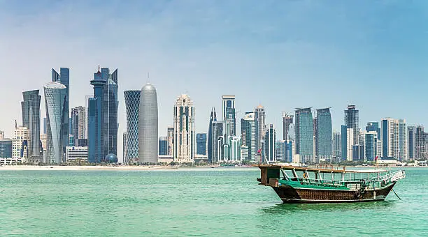 Traditional Dhow cruising in Doha Bay towards Doha Skyscraper Skyline. Doha, Qatar, Middle East. 